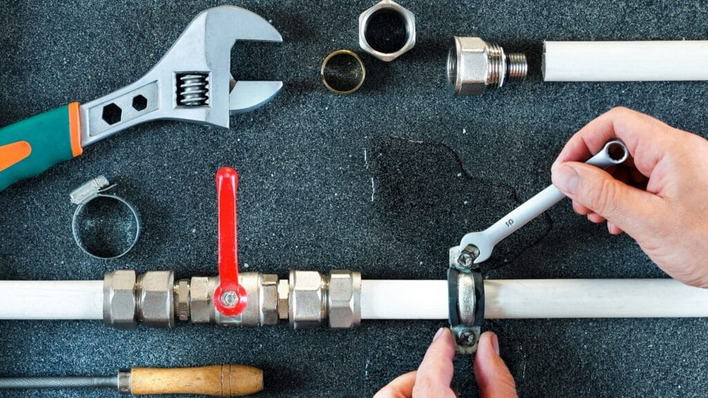 Plumber repairing a pipe valve with an adjustable wrench in Ruskin