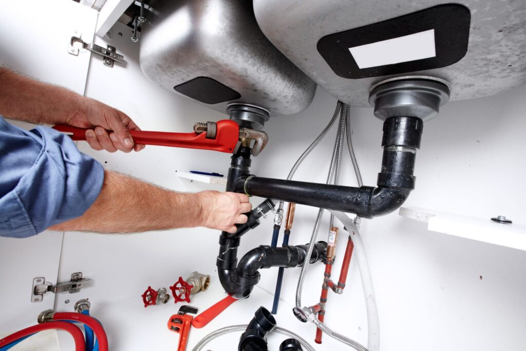 Plumber repairing drain pipes beneath a kitchen sink in Ruskin