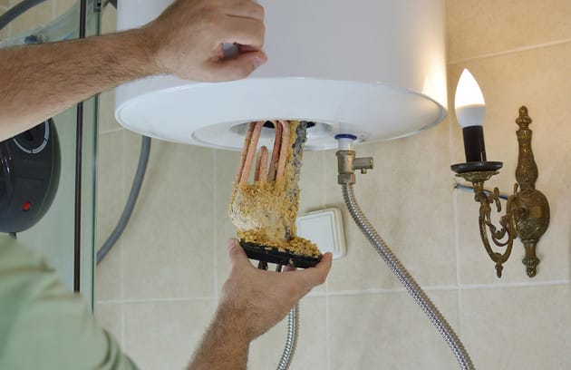 Technician removing mineral buildup from a water heater in Ruskin